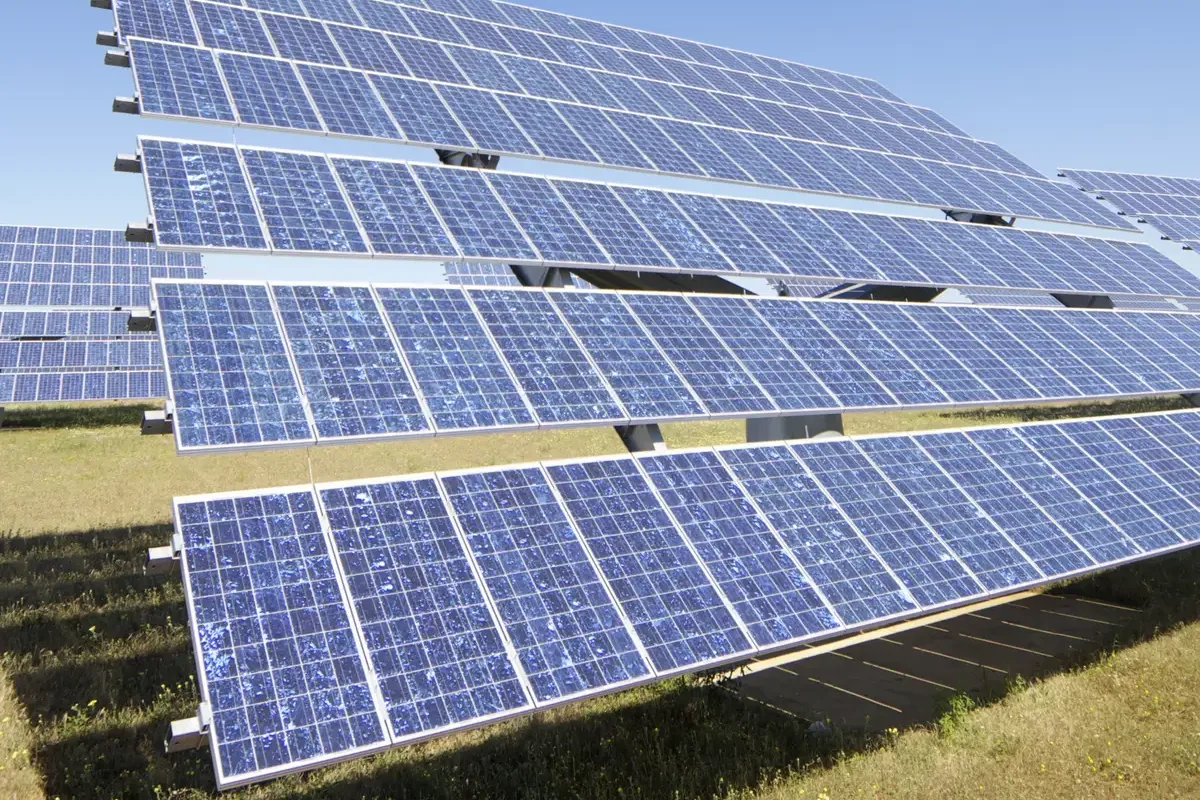 Filas de paneles solares bajo un cielo azul despejado, instalación fotovoltaica de referencia
